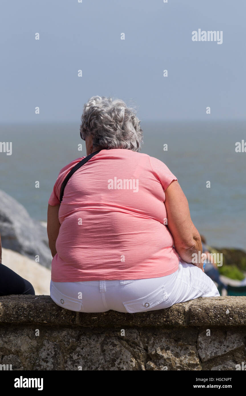 Fat woman sitting on a wall Stock Photo - Alamy