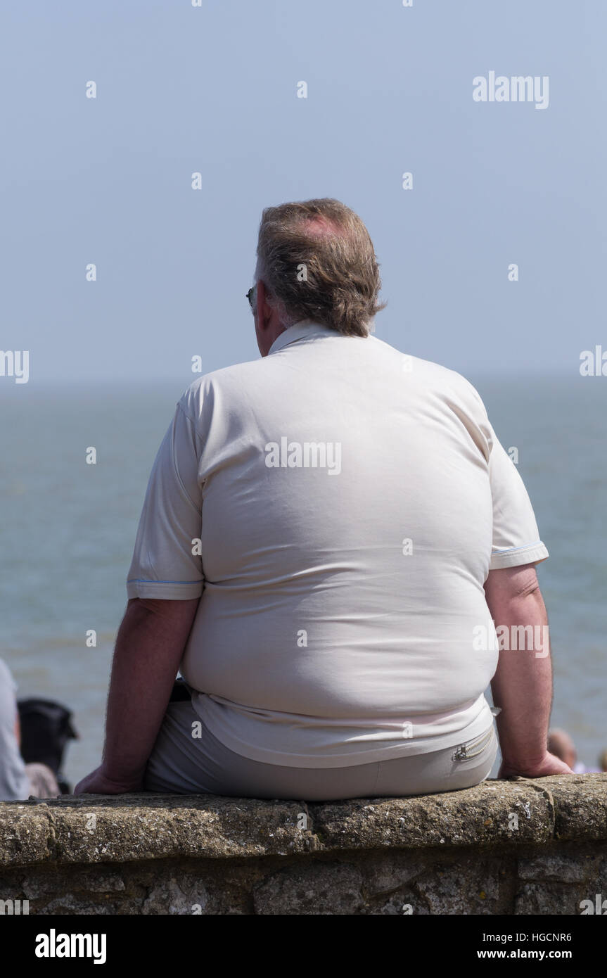 Fat man sitting on a wall Stock Photo