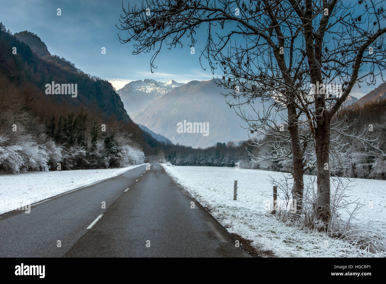 Lonely road running through snowy landscape towards mountains Stock Photo