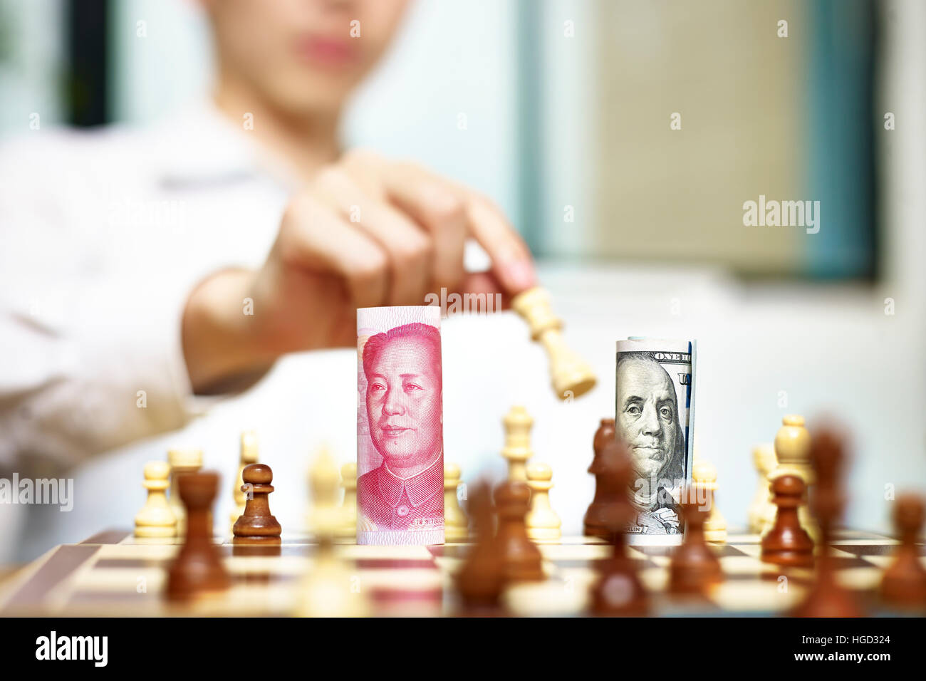 U.S. Dollar (USD) and Chinese Yuan (CNY or RMB) bills on a chess board, concept for currency games. Stock Photo