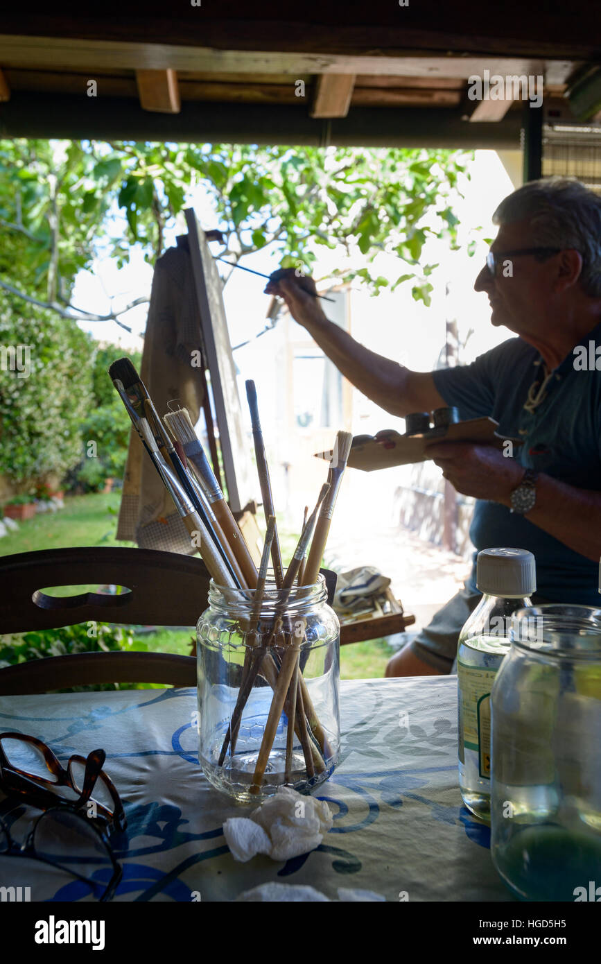 Brush for oil paint, in background Senior Man painting a picture with oil colors Stock Photo