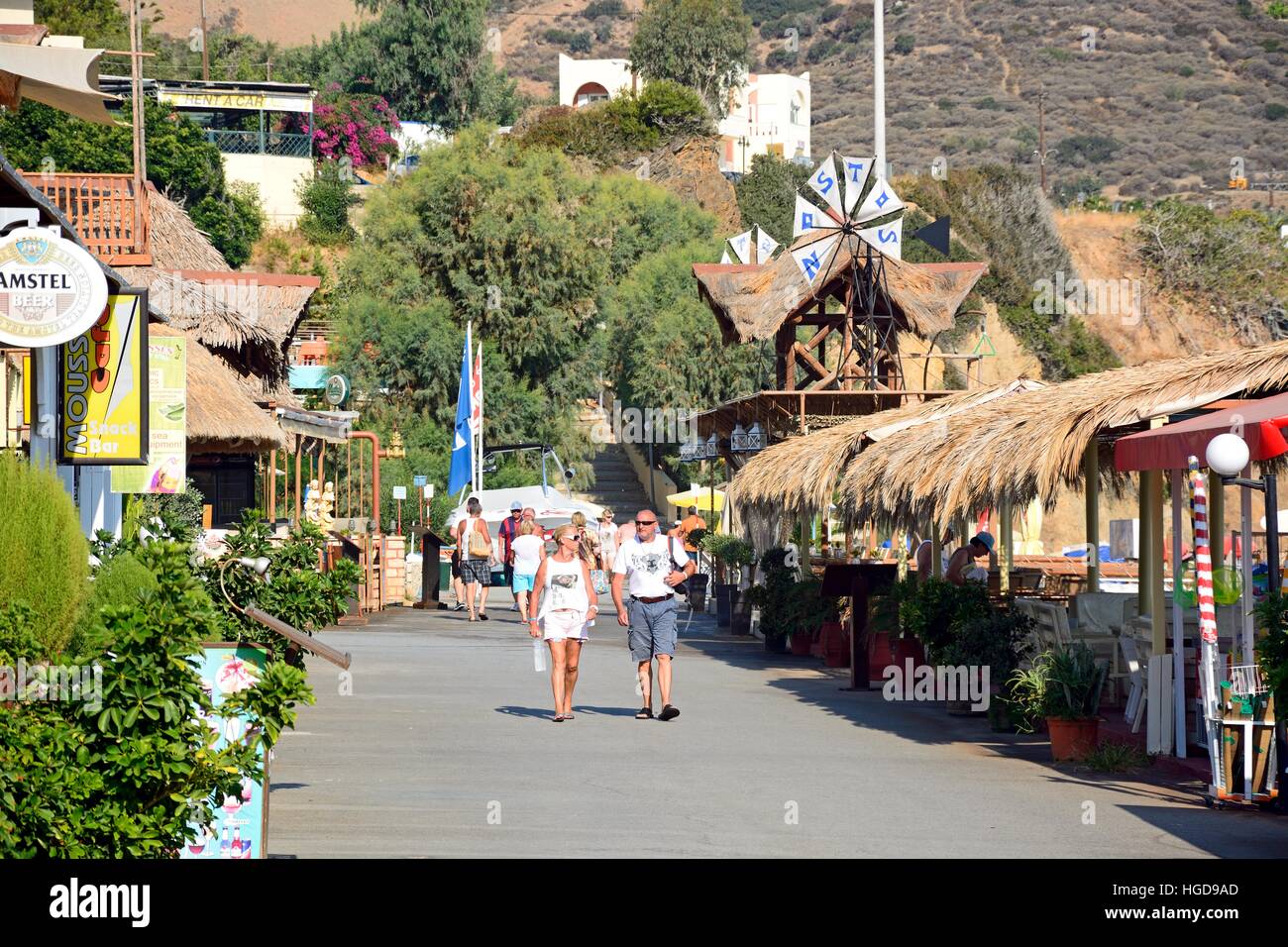 Tourists walking along the restaurant lined promenade at Livadi Beach, Bali, Crete, Greece, Europe. Stock Photo