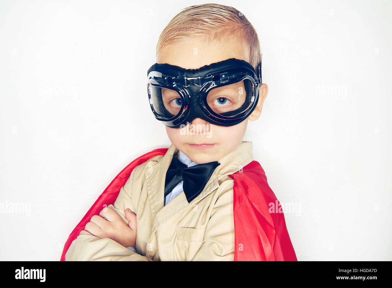 Little boy wearing aviator glasses and red cloak looking confidently at