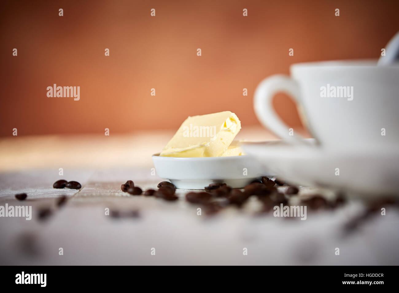 Macro shot of butter for bulletproof coffee with beans on white table Stock Photo