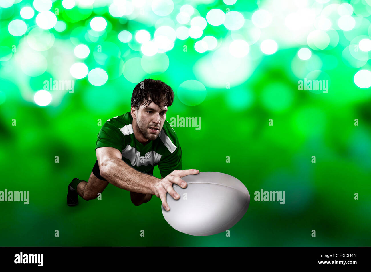 Rugby player in a green uniform scoring on a green lights backgrond ...