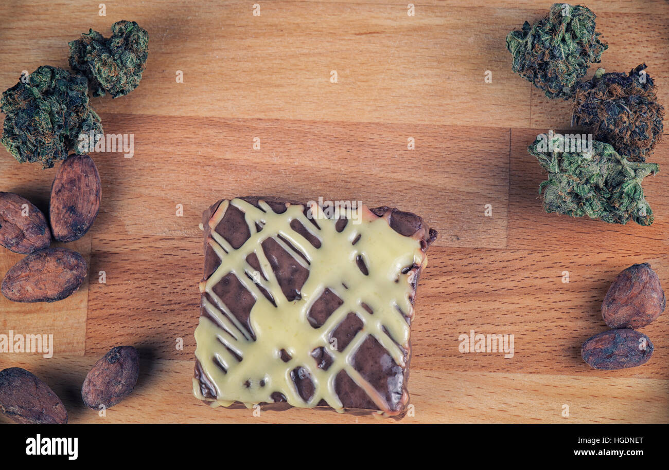 Chocolate pot brownie detail with weed buds in the background Stock