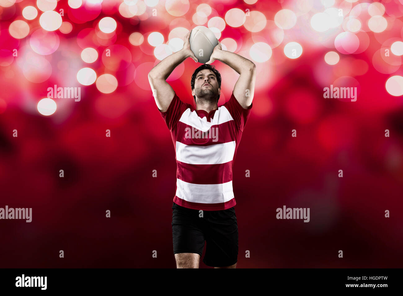 Rugby player in a red uniform on a red lights background. Stock Photo