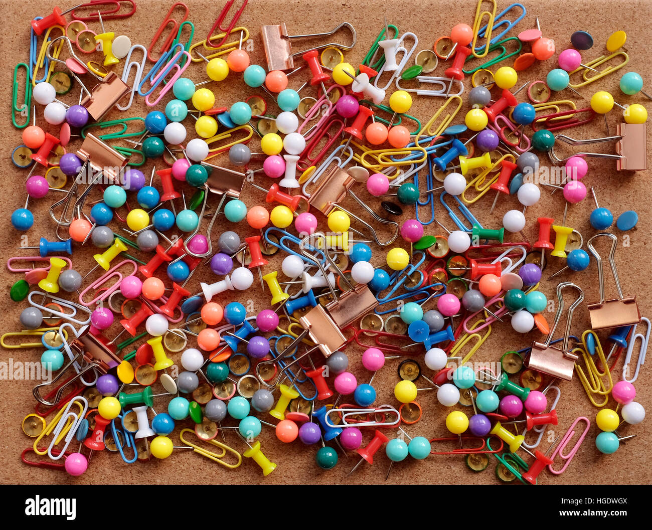 Background of colorful drawing pins, paper clips and metal binder clips on a cork board Stock