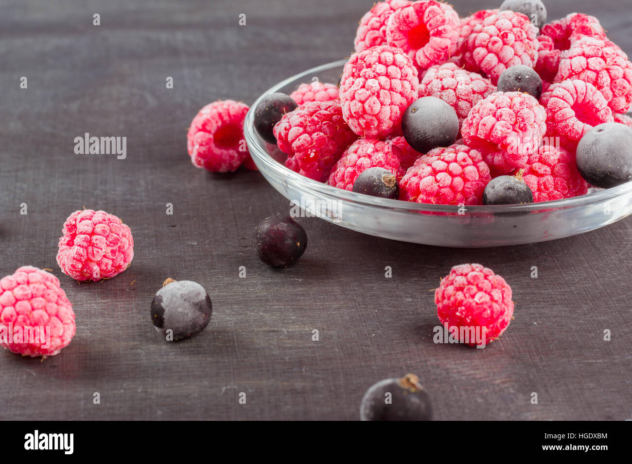 Frozen raspberries in a glass saucer. Frost on the berries. Dark ...