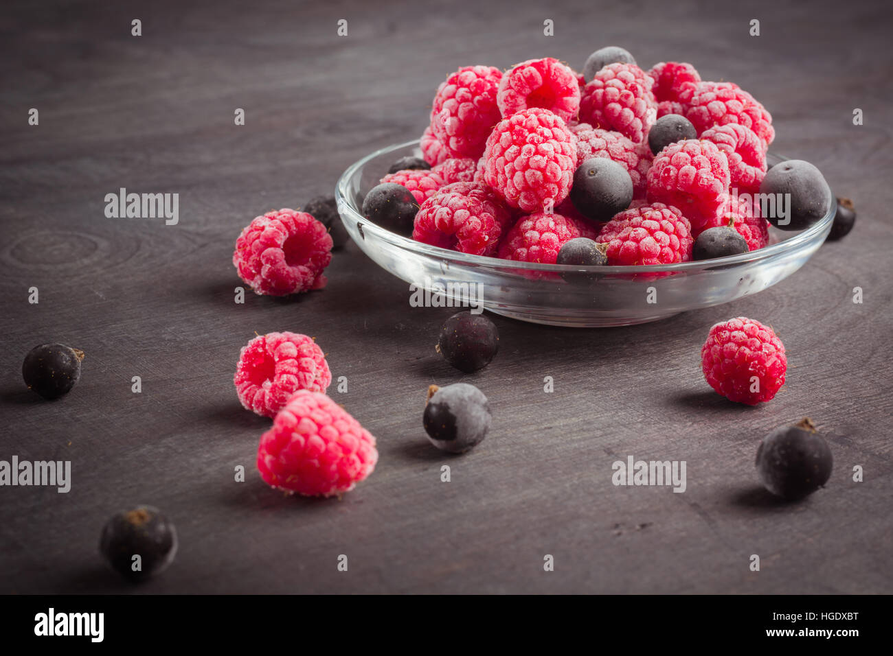 Frozen raspberries in a glass saucer. Frost on the berries. Dark ...
