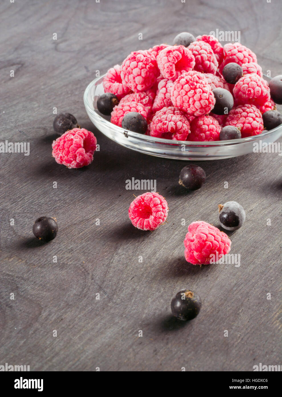 Frozen raspberries in a glass saucer. Frost on the berries. Dark ...