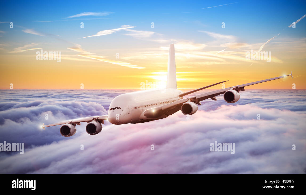 Huge commercial airplane flying above clouds in dramatic sunset light ...