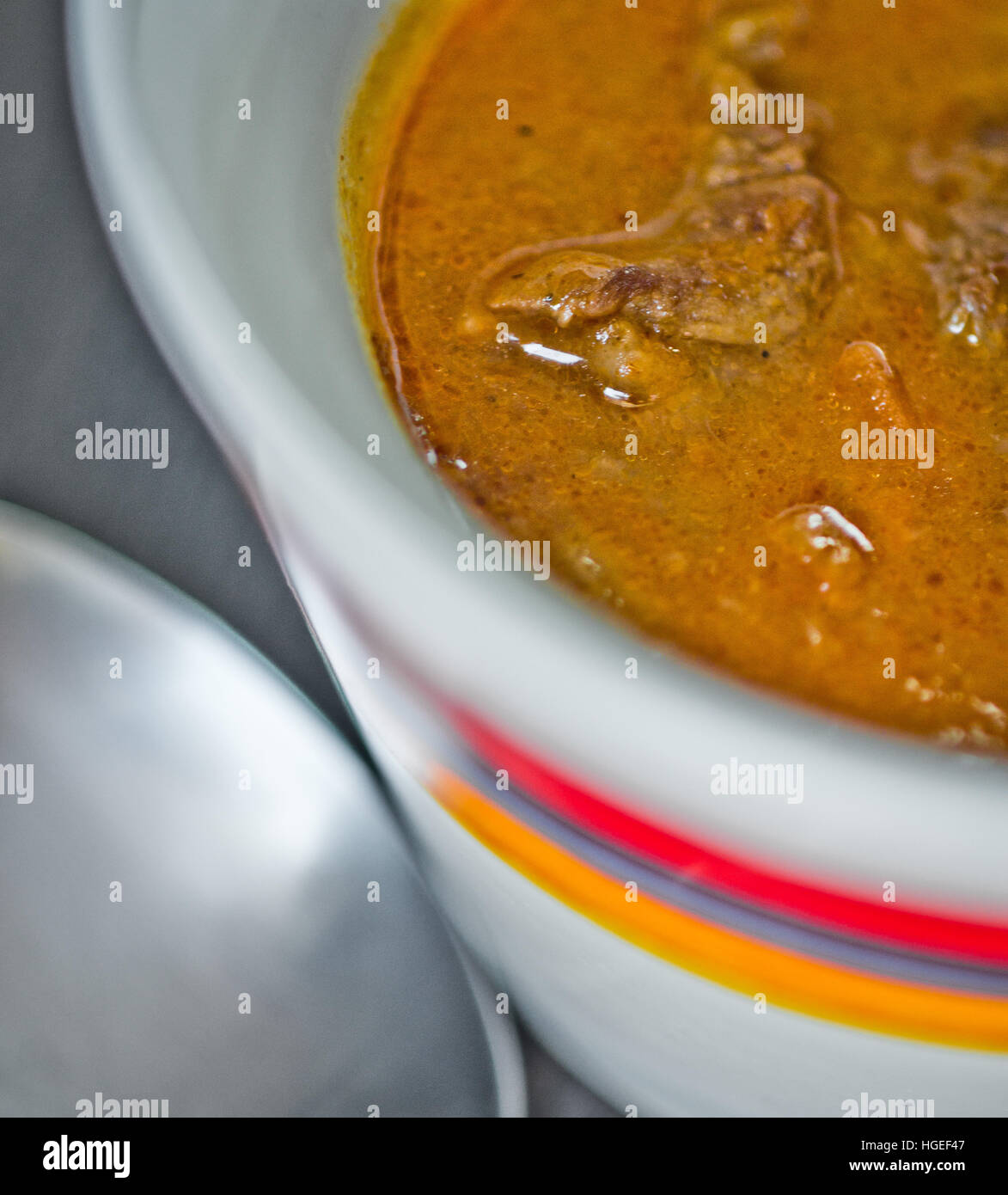 cup of tasty soup, hot and steaming with beef, vegetables, curry, turmeric and clove seeds Stock Photo
