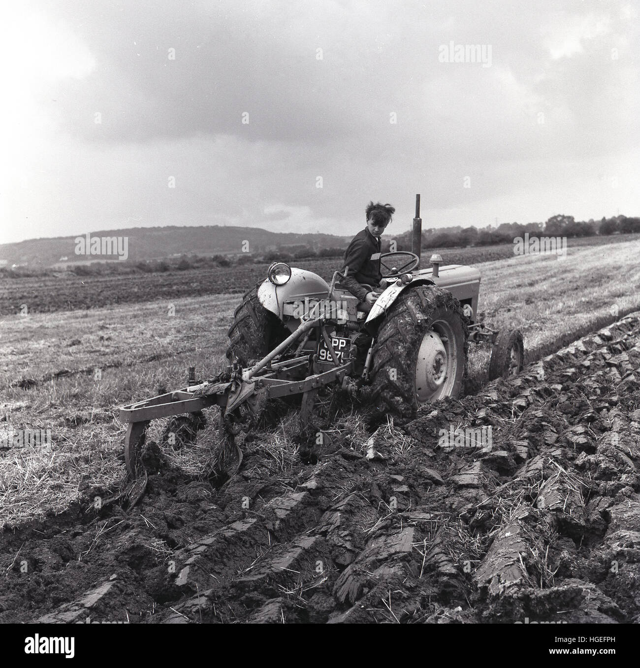 1960s, historical, young lad on a tractor ploughing a field, ie turning the soil to make furrows. Stock Photo