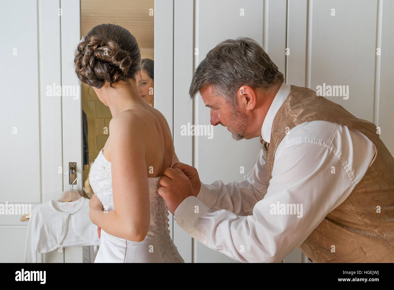 groom helps the bride to dress Stock Photo
