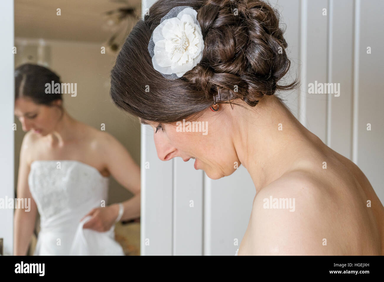 A beautiful bride dresses herself in front of the mirror Stock Photo