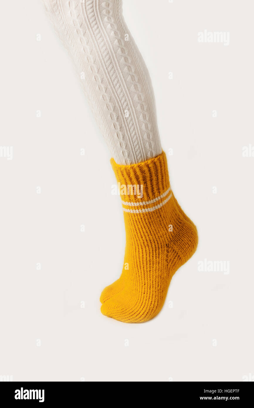 Female legs in white stockings and yellow knitted socks. Stock Photo