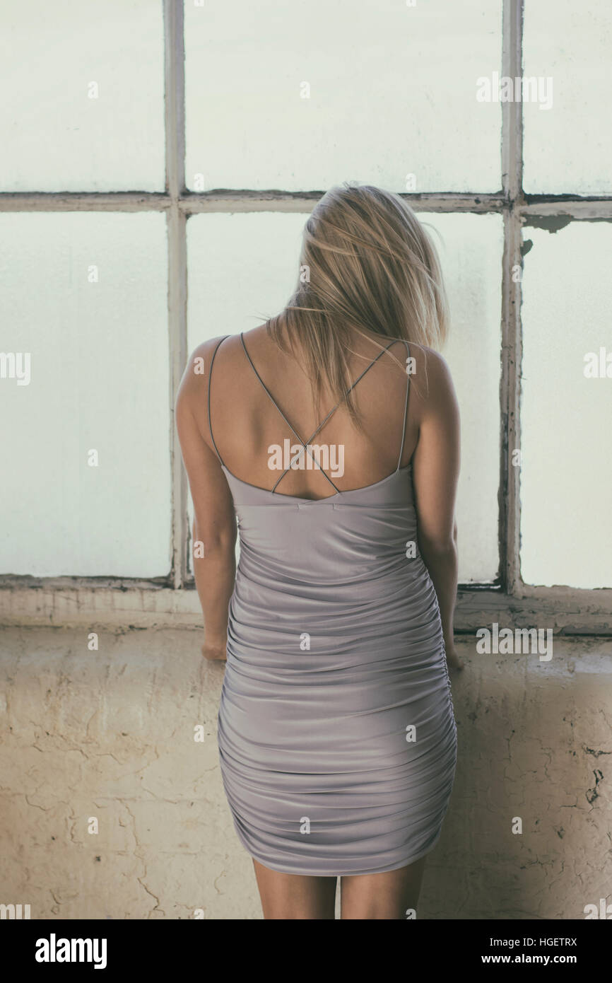 Rear view of a blond woman standing by the window Stock Photo - Alamy