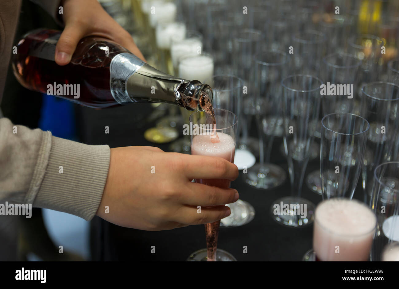 person pouring champagne in a row of glasses during a party for celebration Stock Photo