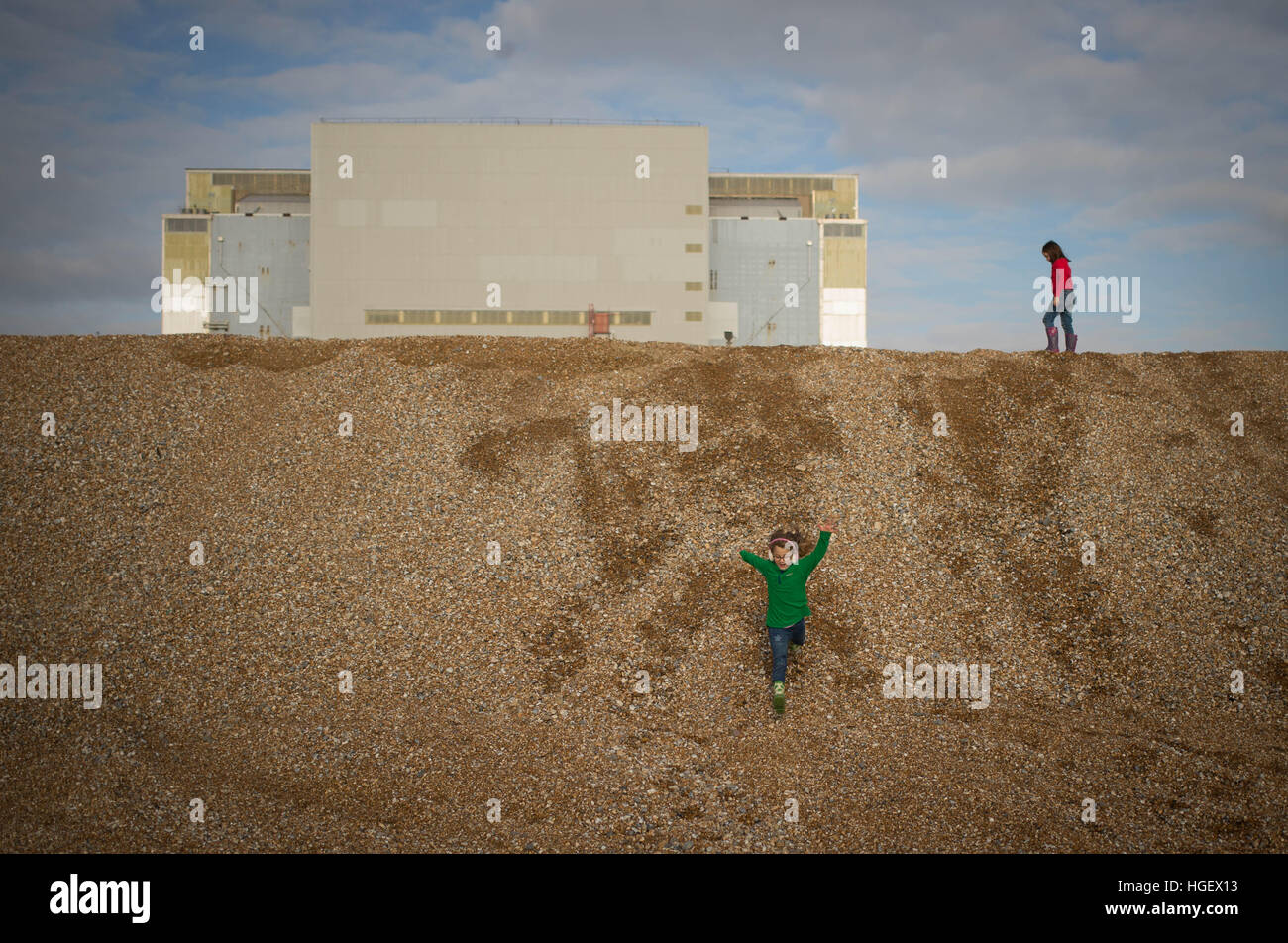 Children play on the shingle beach outside Dungeness Power Station in Kent, England, Great Britain Stock Photo
