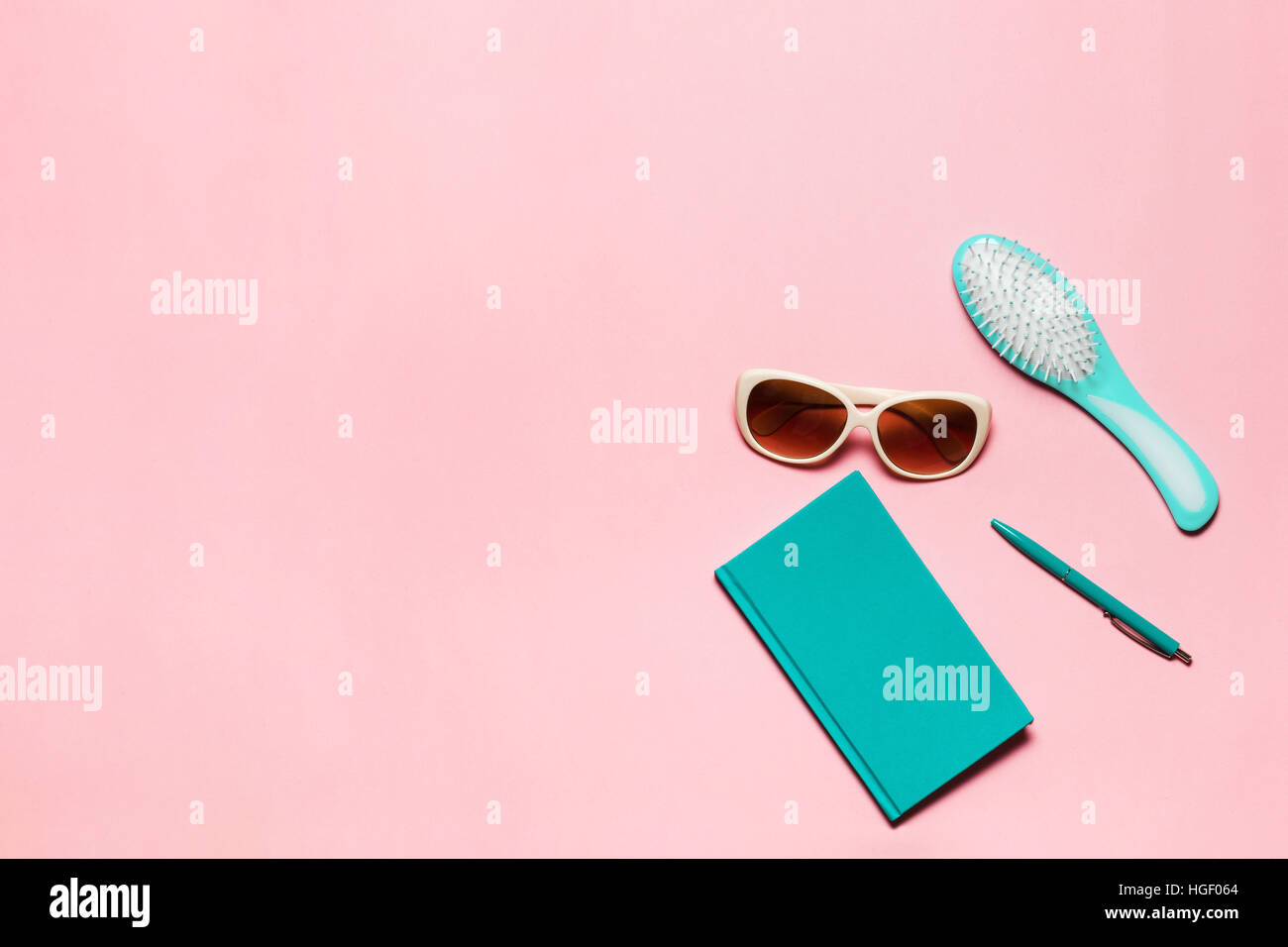 Feminine turquoise colored accessory of hairbrush, glasses, diary and pen isolated on pink copy space. Stock Photo