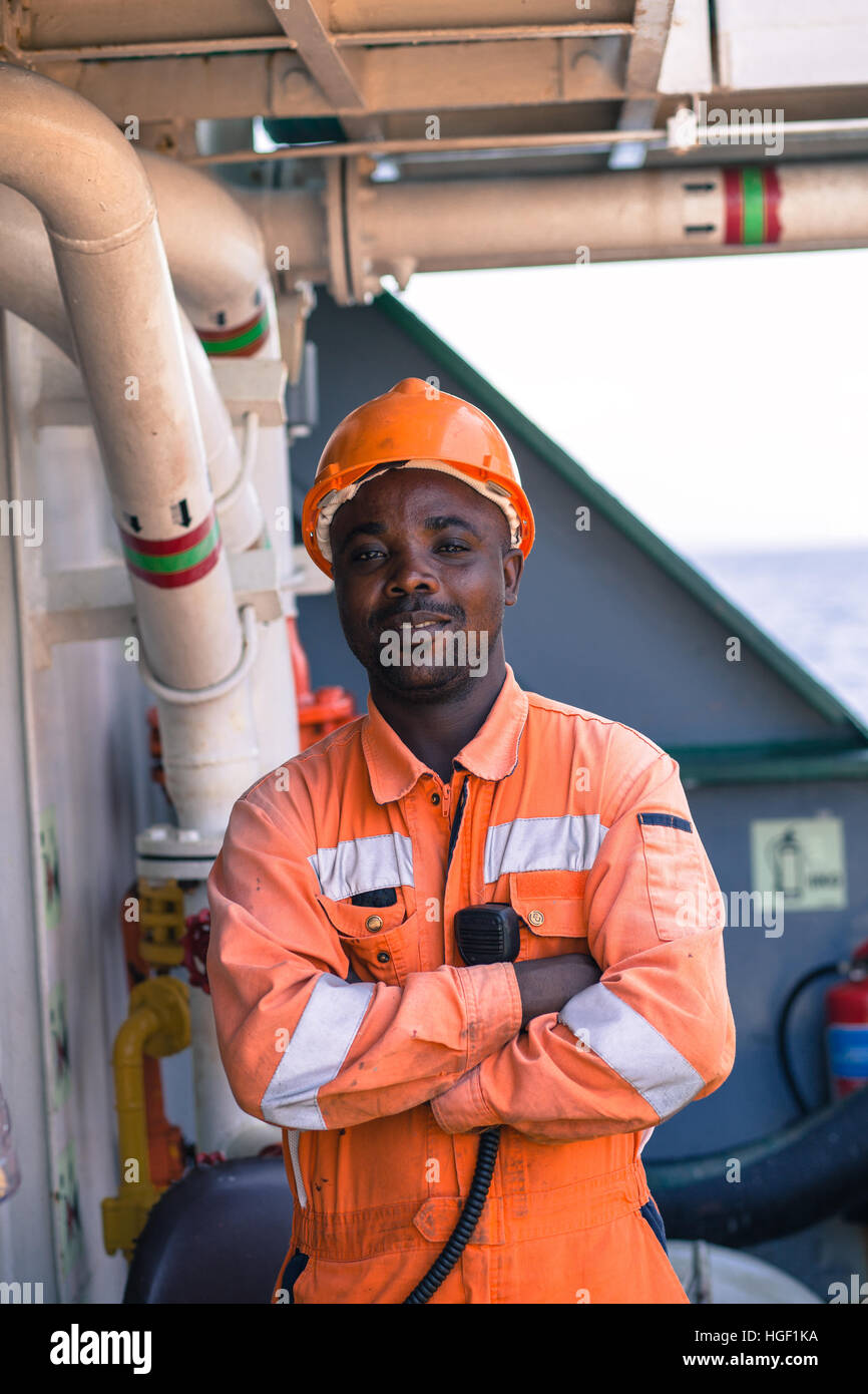 young African seaman standing on deck dressed in coverall and safety