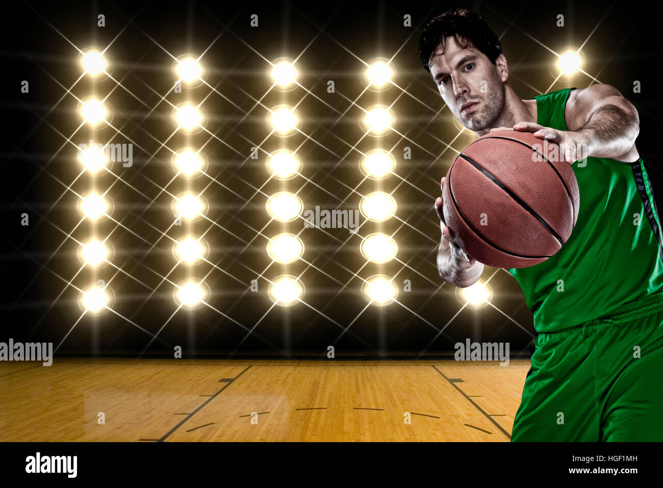 Basketball player on a green uniform, in front of lights Stock Photo