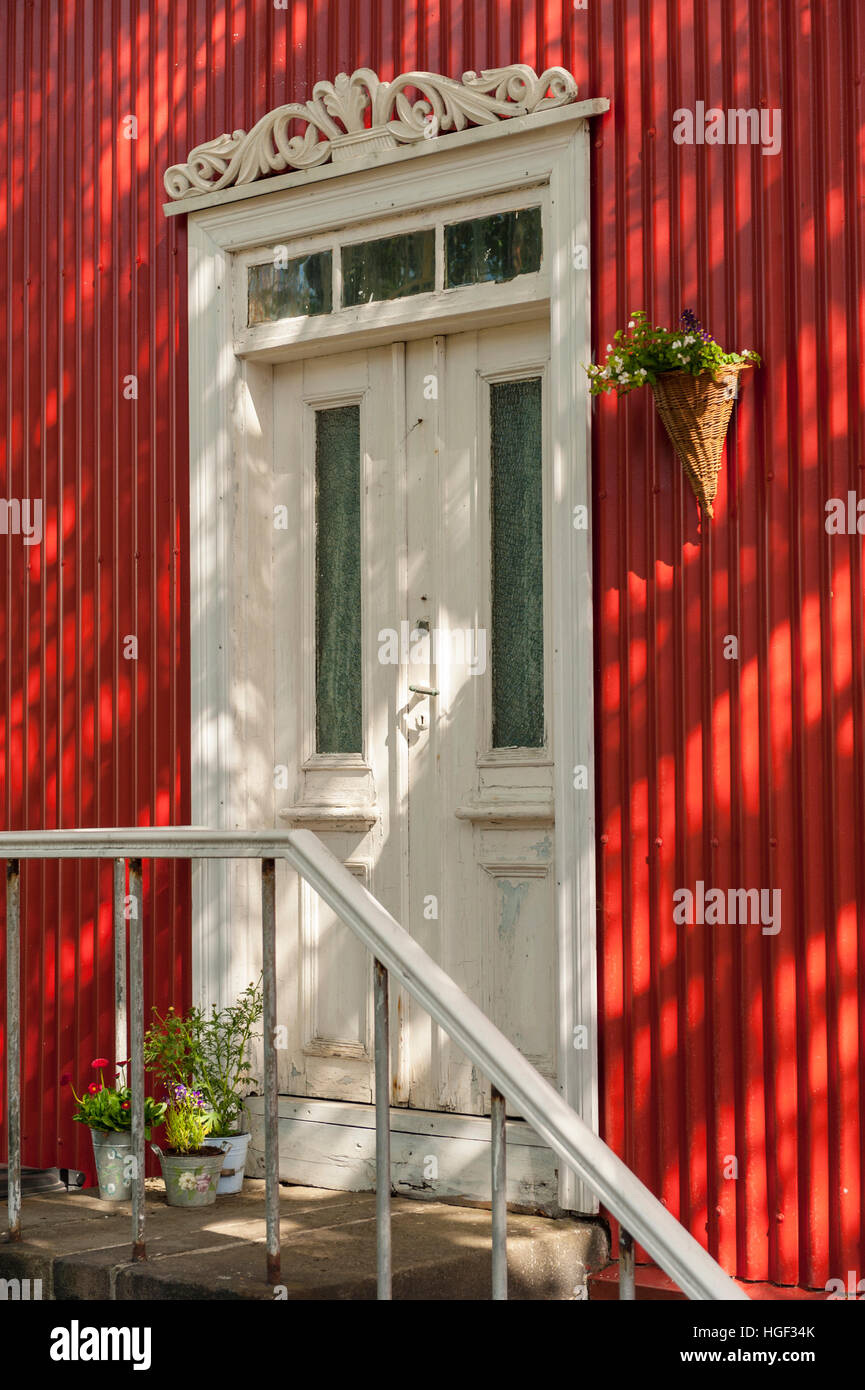 An old white door surrounded by bright red metal siding in Reykjavik, Iceland. Stock Photo