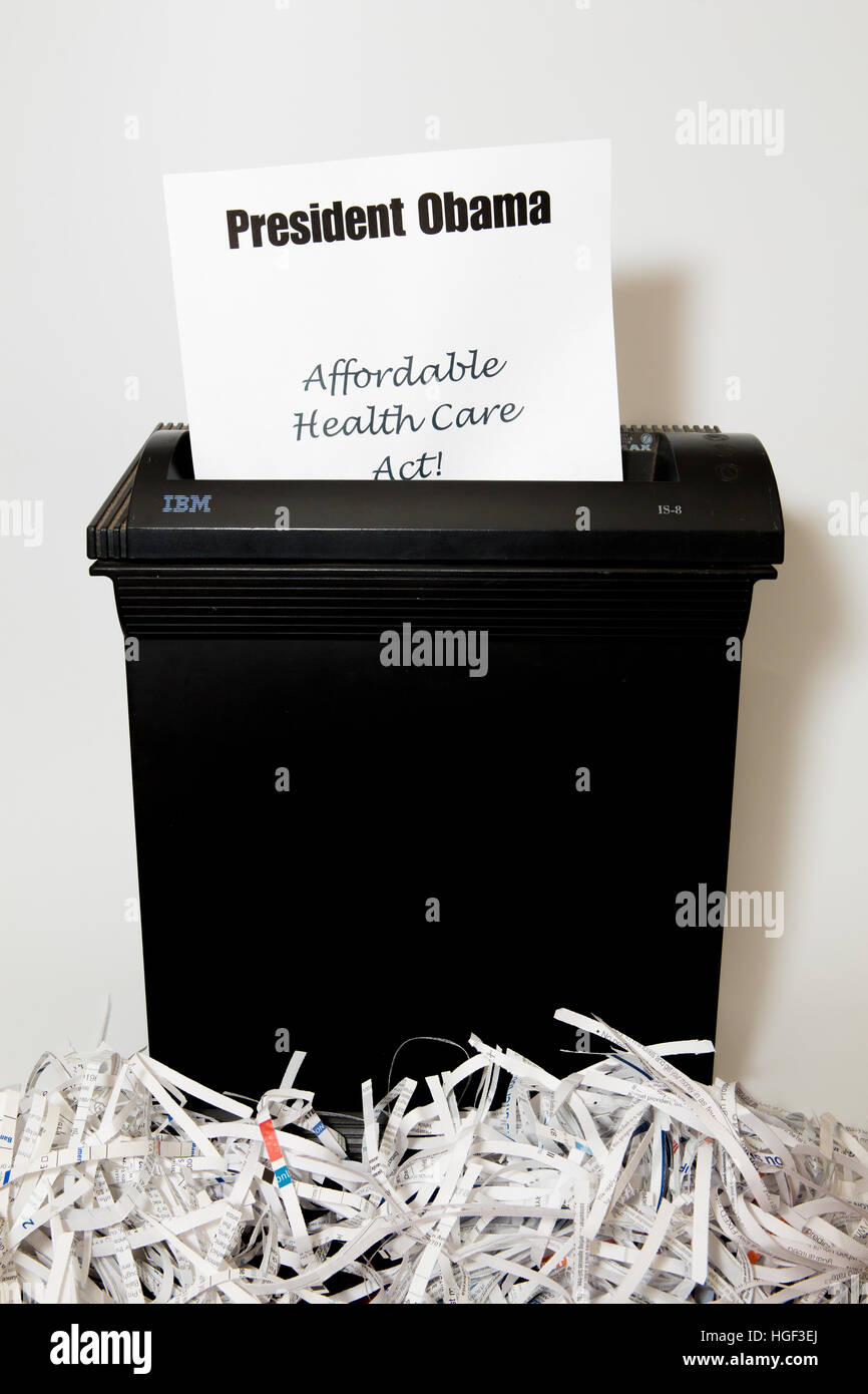 President Obama text headed paper with affordable health care act below disappearing into a paper shredder Stock Photo