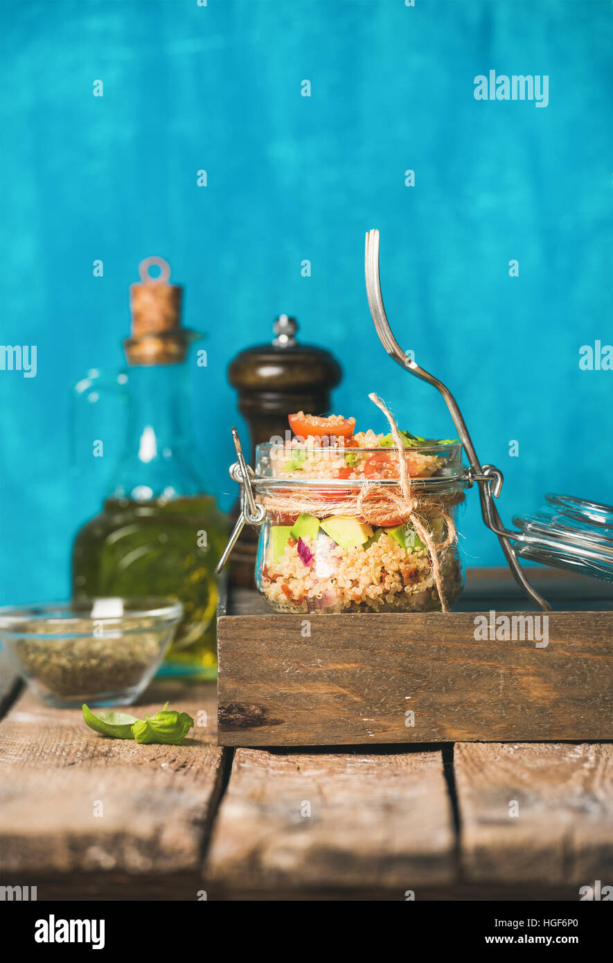 Healthy homemade jar quinoa salad with tomatoes, avocado and fresh basil. Detox, dieting, vegetarian, vegan, clean eating food concept. Bright blue ba Stock Photo