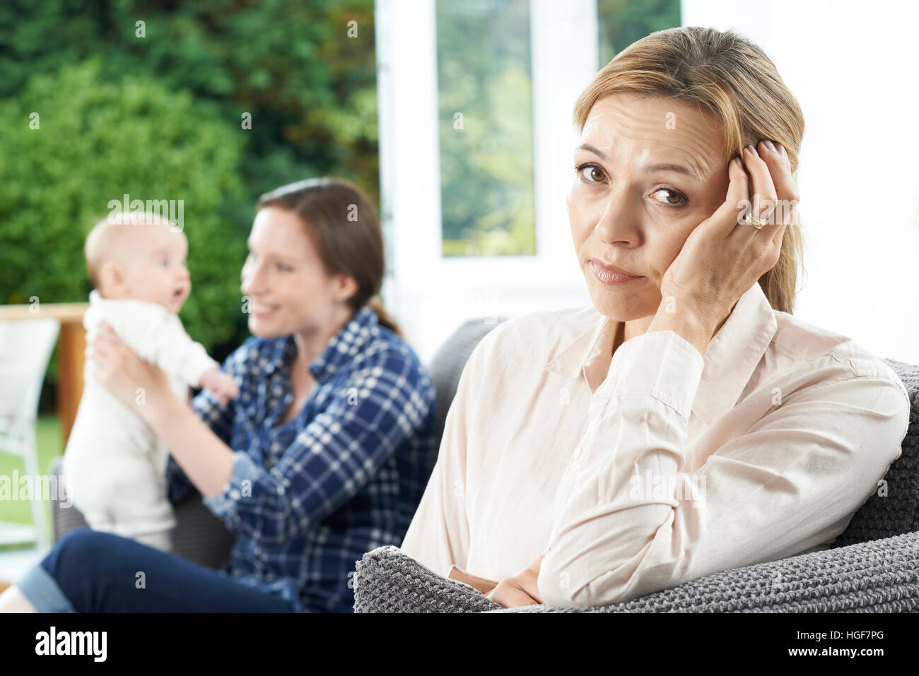 Sad Mature Woman Jealous Of Mother With Young Baby Stock Photo