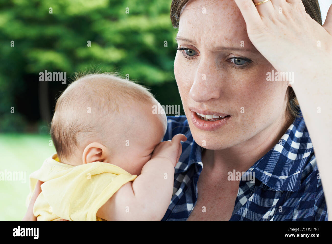 Forgetful Mother Holding Baby Girl At Home Stock Photo