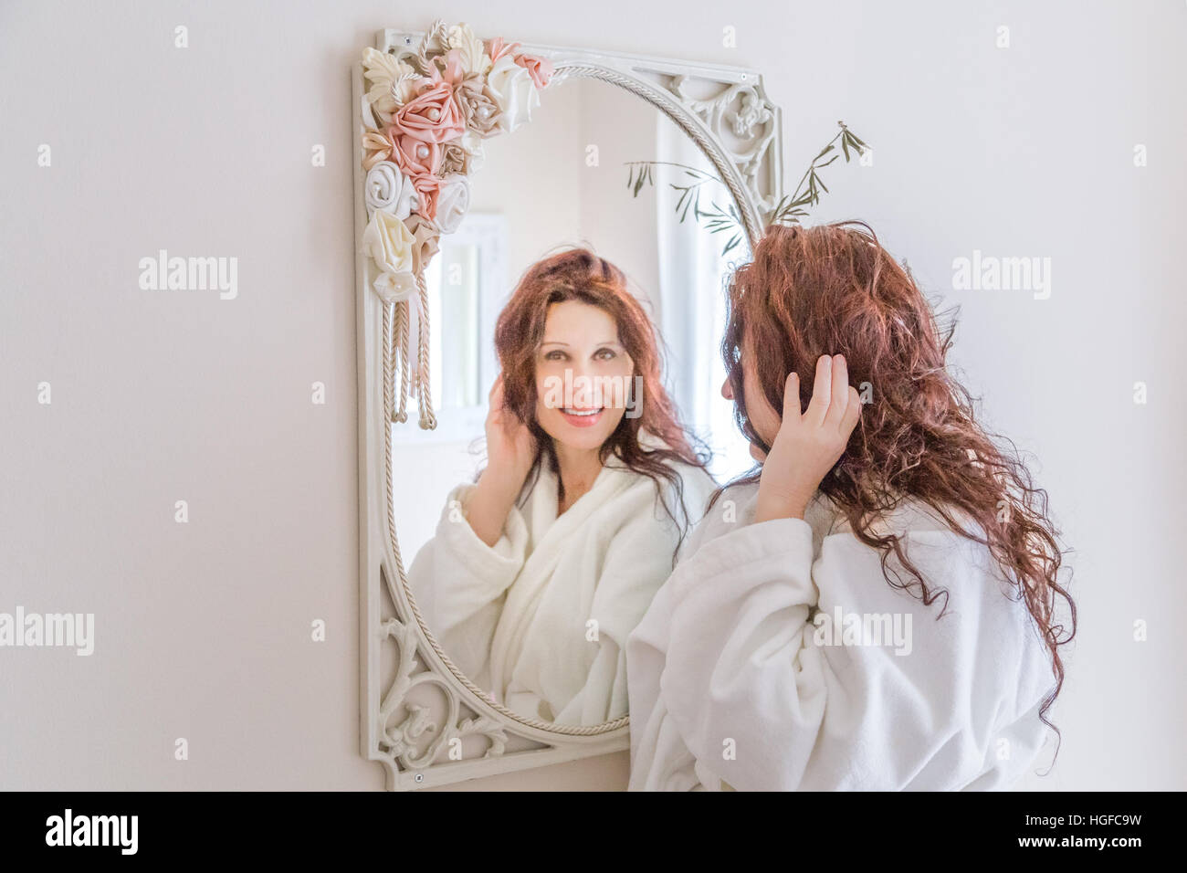mature menopausal woman touching her hair in the mirror Stock Photo