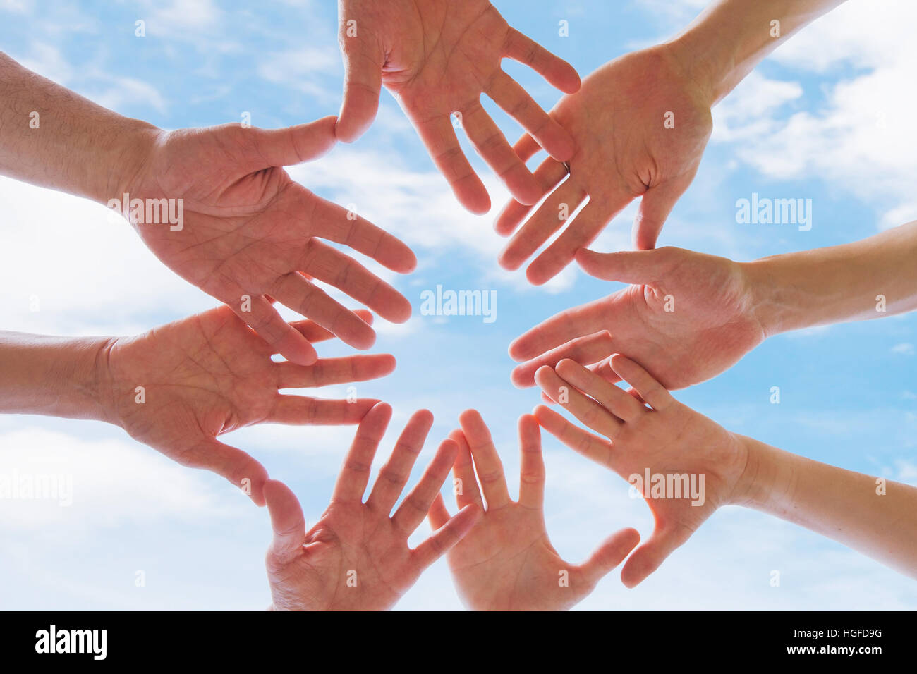 team or brotherhood concept, group of people putting hands together against blue sky Stock Photo
