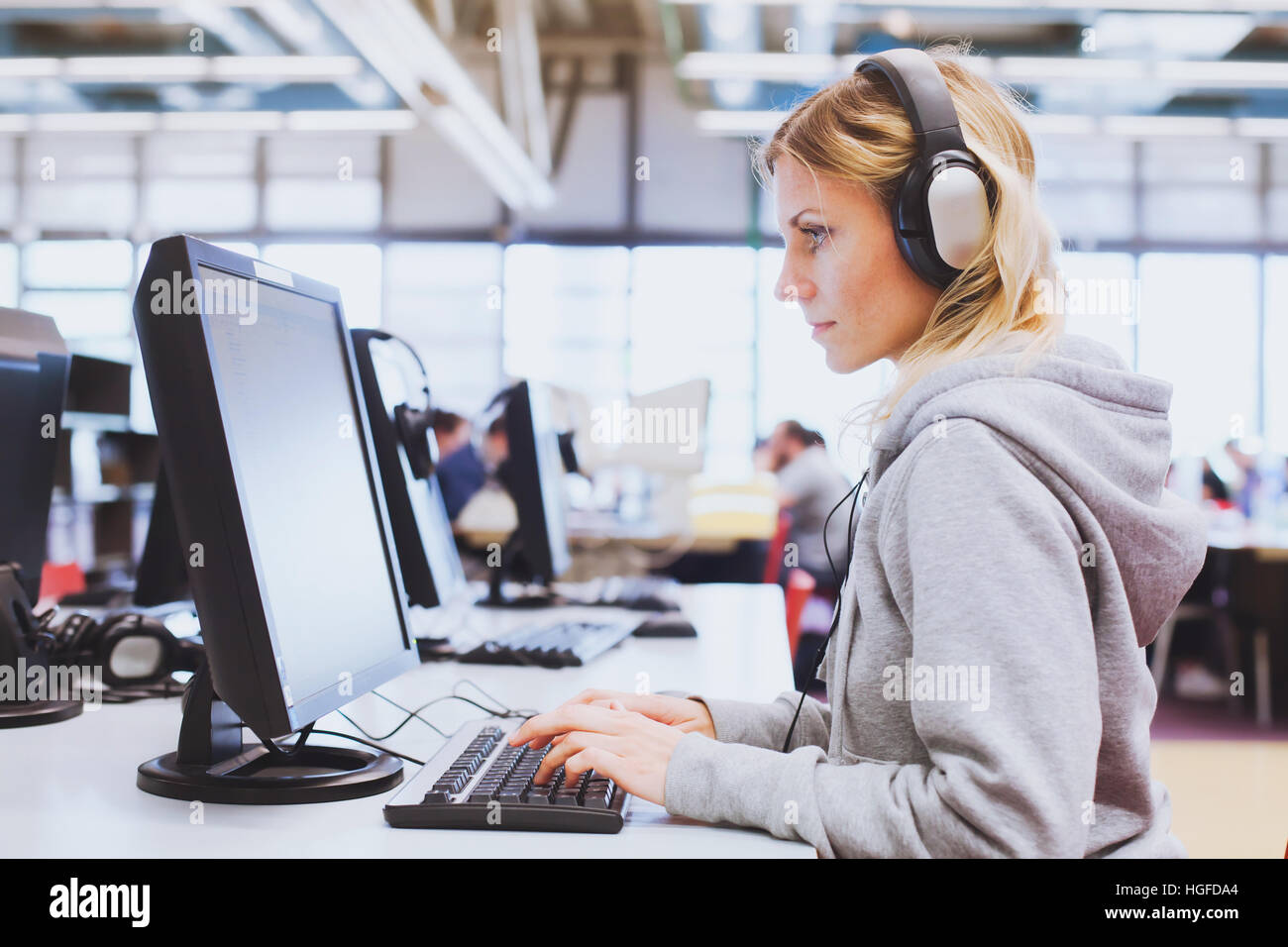 adult education, student in headphones working on computer in the library or classroom of university Stock Photo