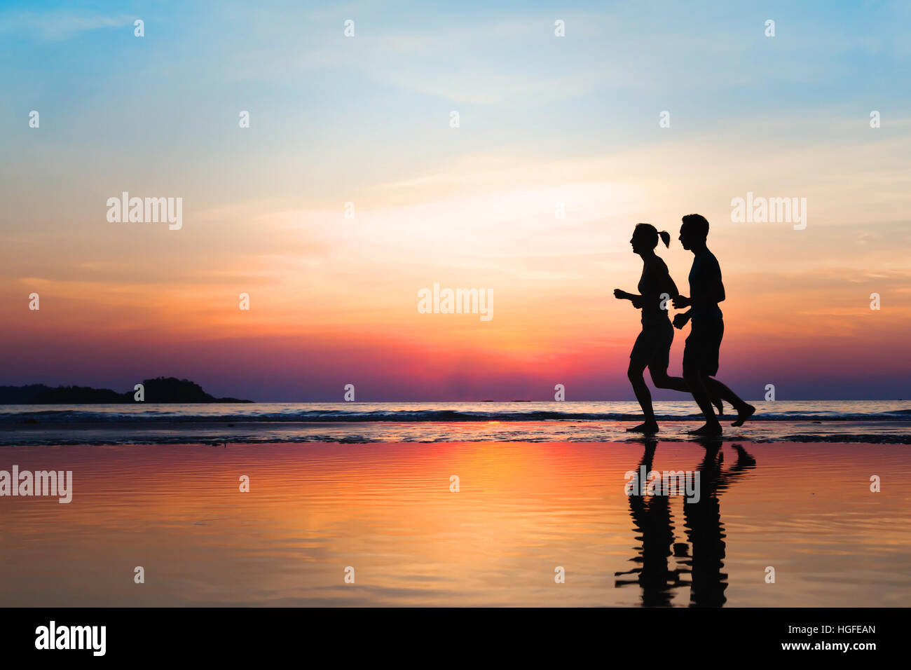 jogging and healthy lifestyle, two runners silhouettes on the beach at sunset, workout and sport Stock Photo