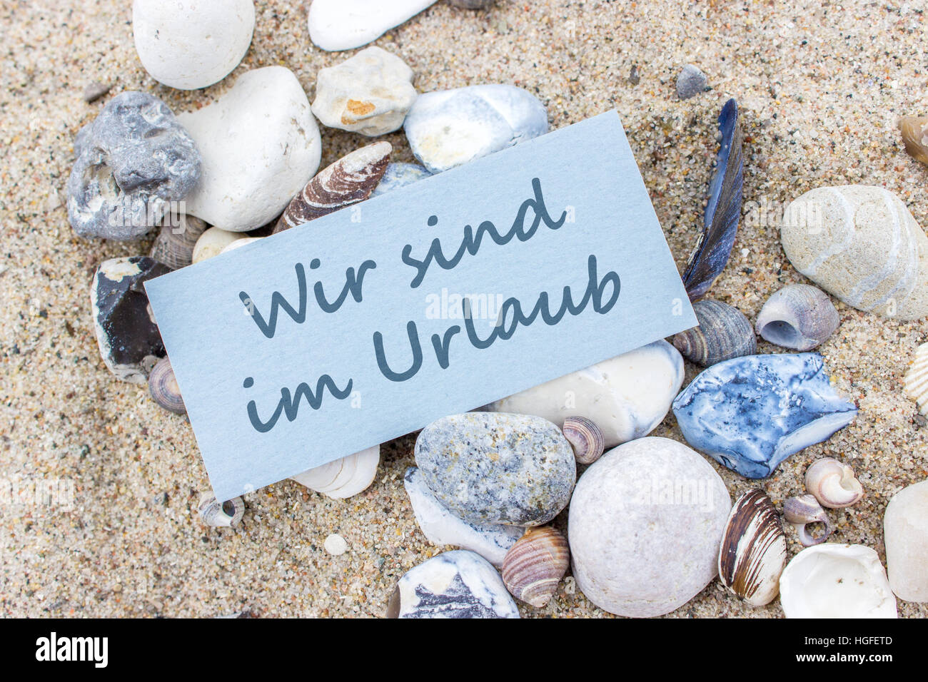 Card with german text "We're on vacation" in beach sand Stock Photo Alamy