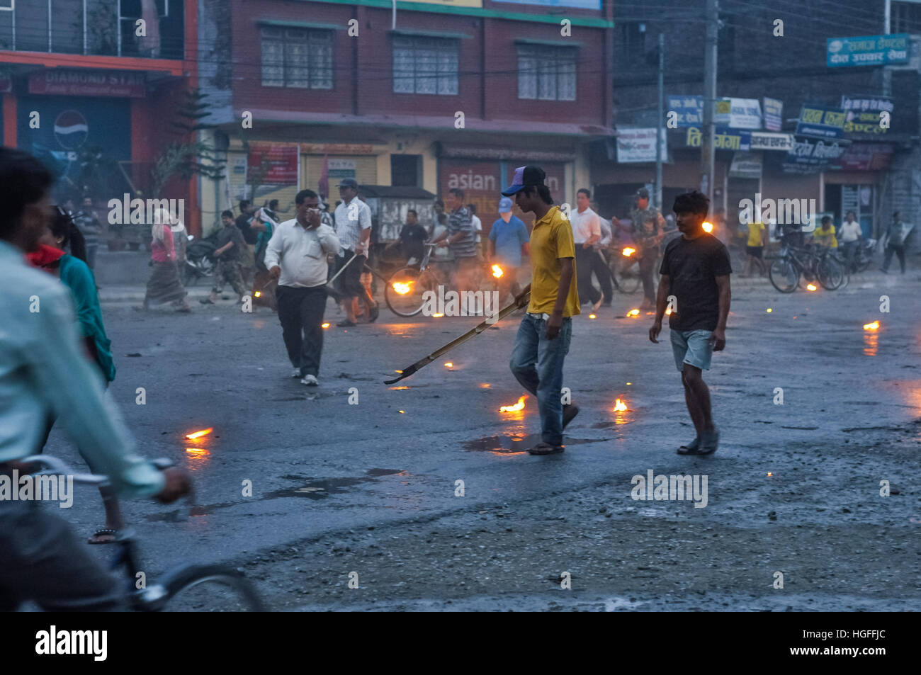 Nepal - circa May 2012: Photo of people walking or riding bicycles on street with burning torches in hands on rainy day during Nepal general strike. D Stock Photo