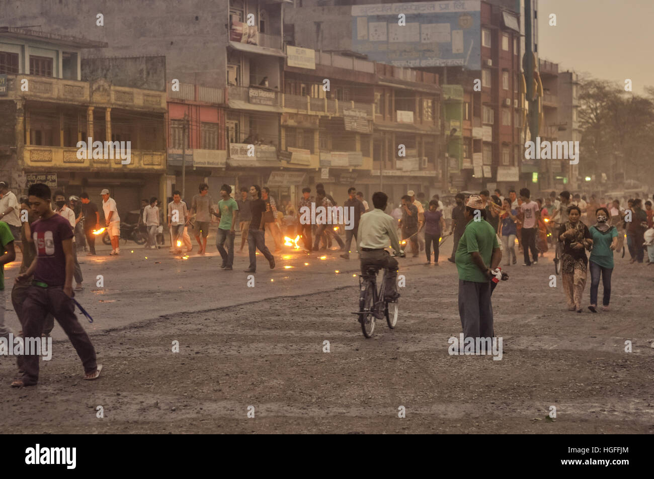Nepal - circa May 2012: Native people walk or ride bicycles on street and hold burning torches in hands on rainy day during Nepal general strike. Docu Stock Photo