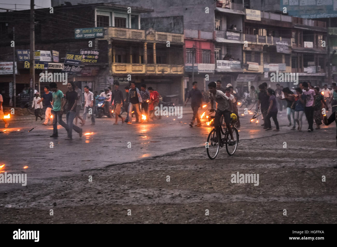 Nepal - circa May 2012: Native people walk or ride bicycles on street and hold burning torches in hands on rainy day during Nepal general strike. Docu Stock Photo