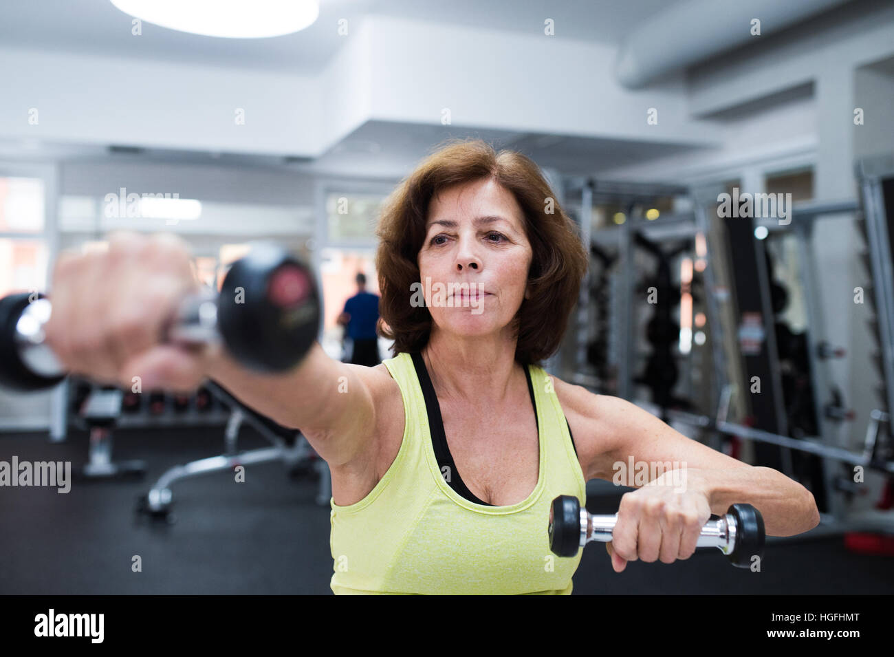 Senior woman in gym working out with weights Stock Photo - Alamy