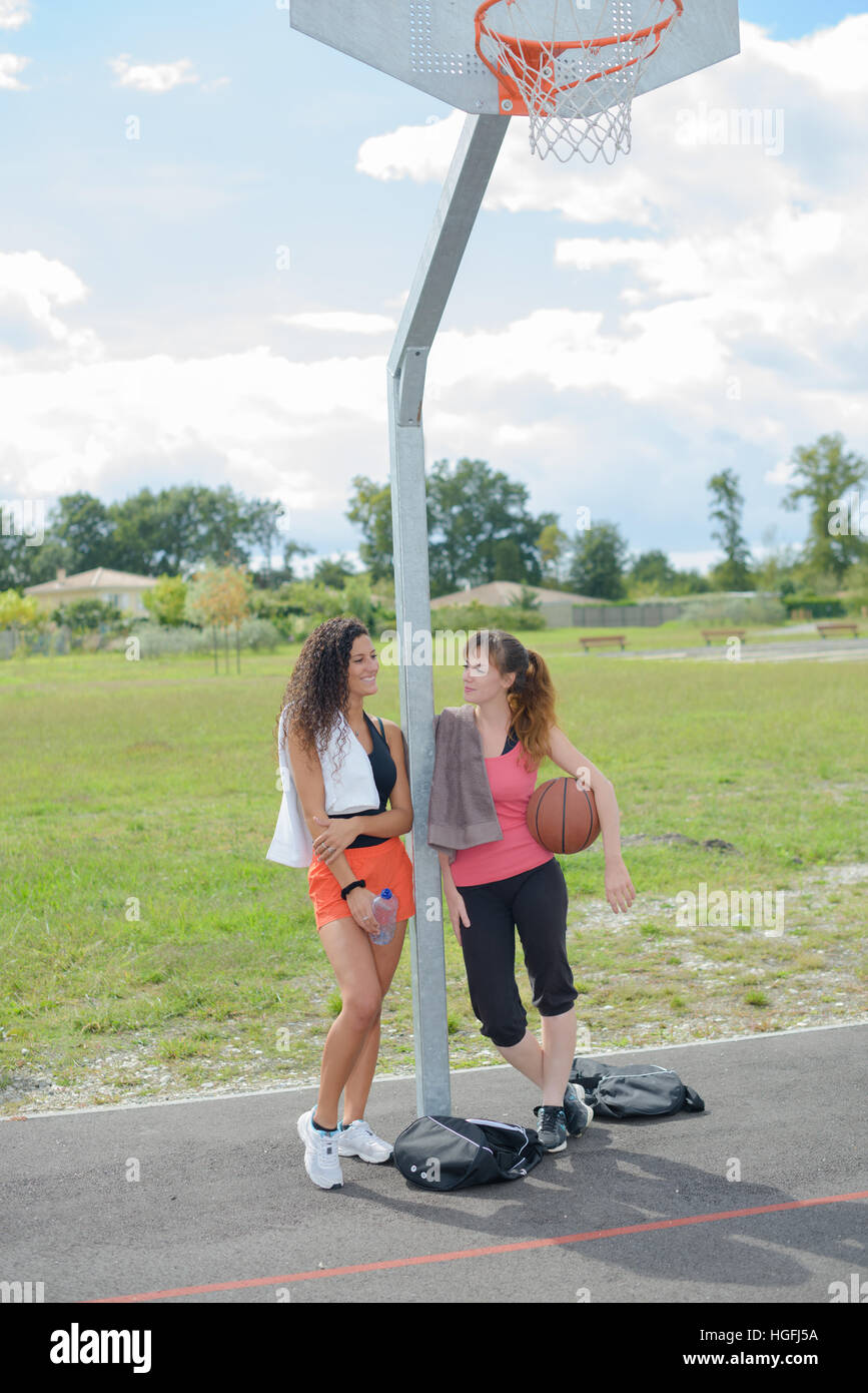 Ladies leaning against post of basketball net Stock Photo Alamy