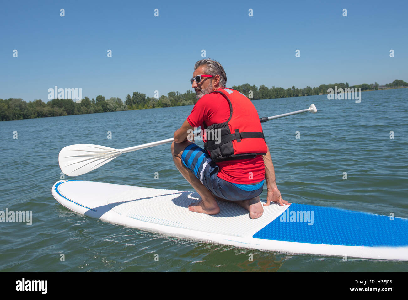 mature attractive rider contemplating nature sitting on paddle board Stock Photo