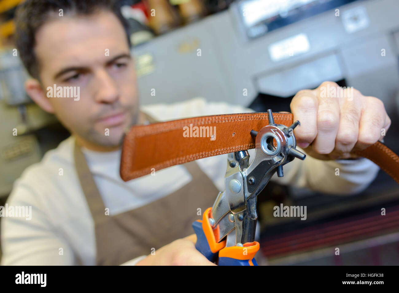 Cobbler punching holes in leather belt Stock Photo Alamy