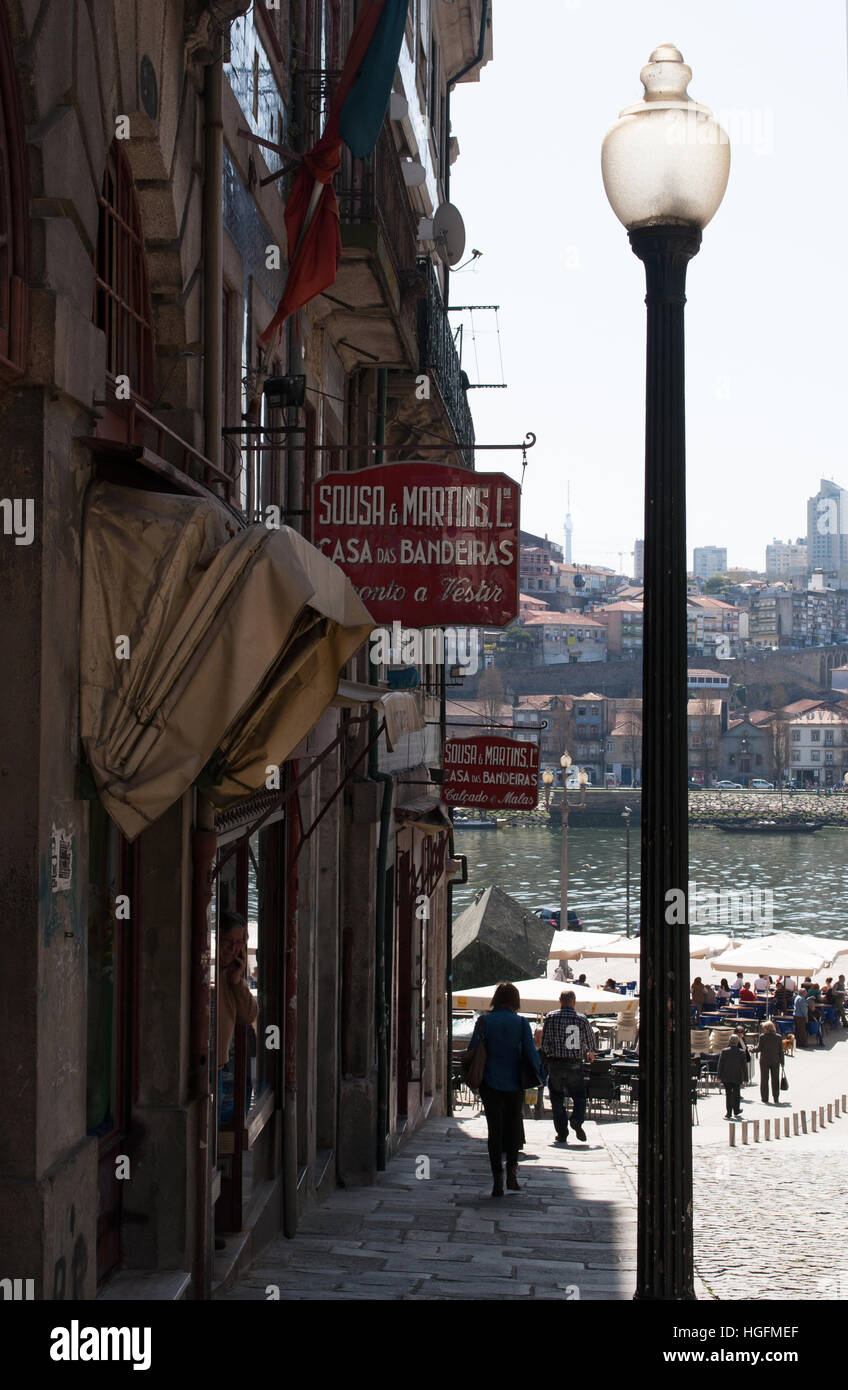 Porto: a street lamp and an old man walking towards the central Praca da Ribeira with view of the signs of craft shops Stock Photo