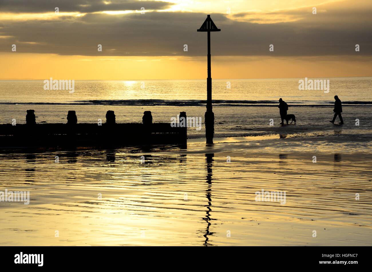 people walking a dog on Borth beach at sunset Ceredigion Wales Cymru UK GB Stock Photo