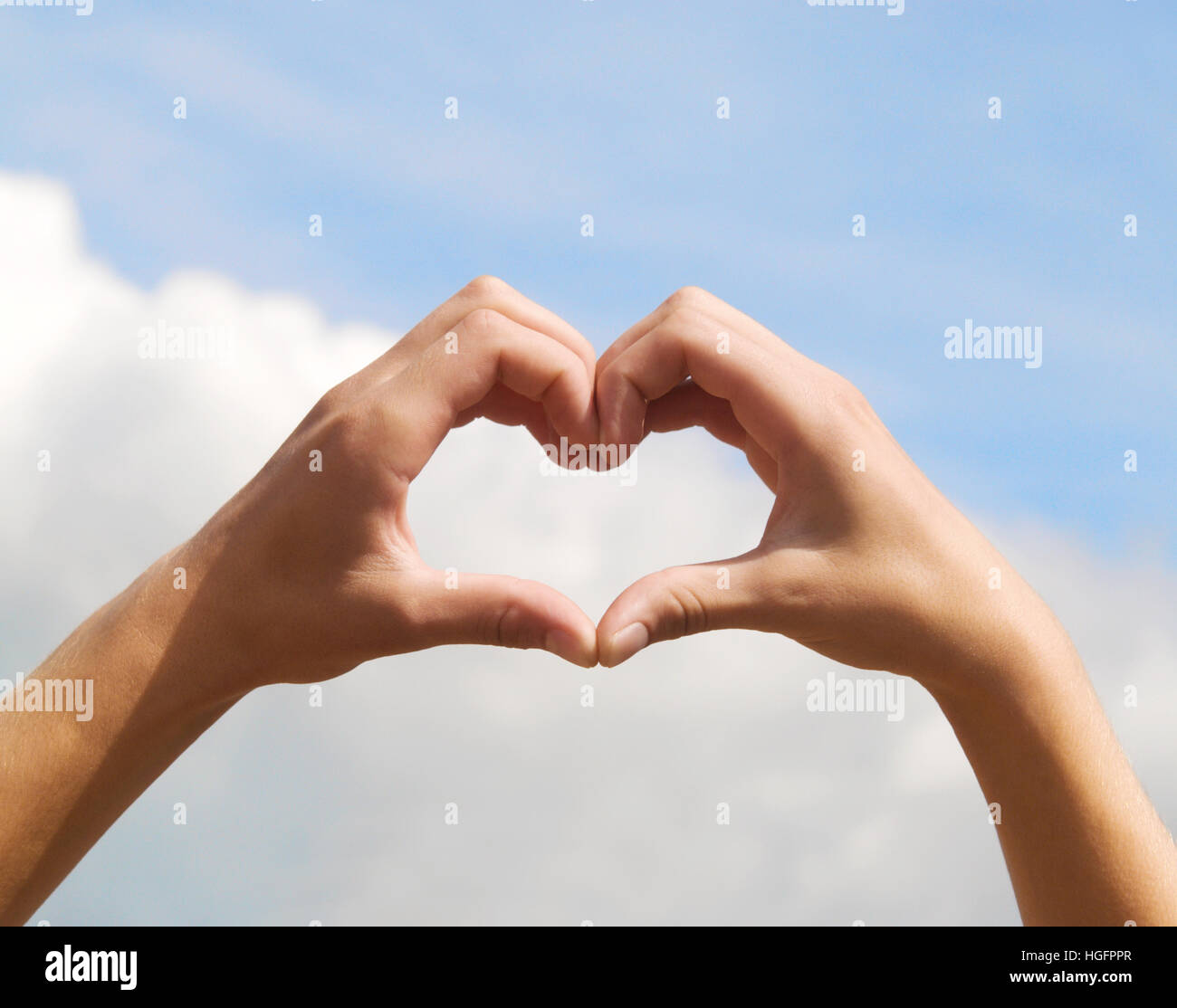 hands in form of heart on blue sky background Stock Photo - Alamy
