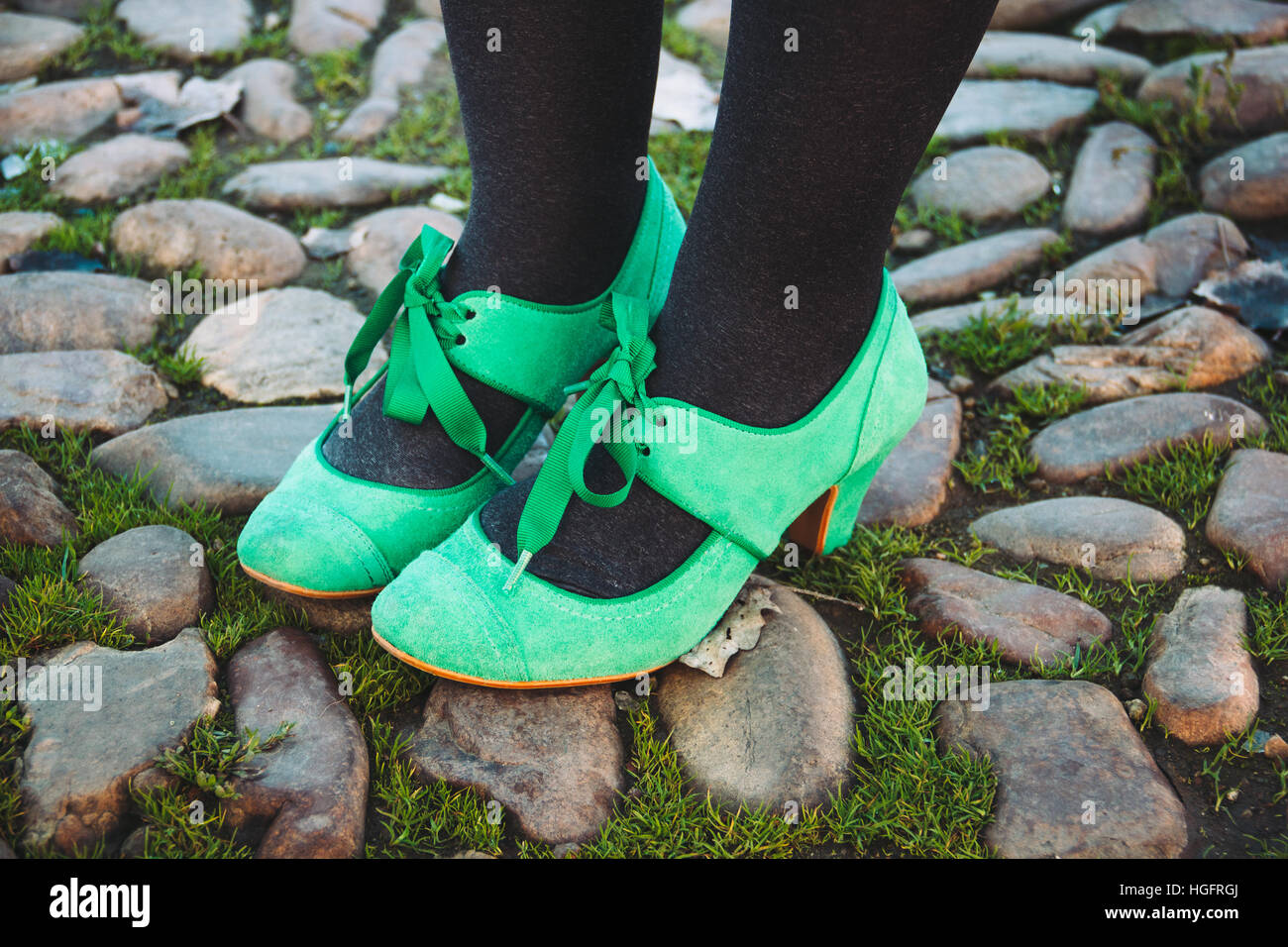 Close up of feet wearing bright green Mary Jane heeled shoes on a cobbled street Stock Photo