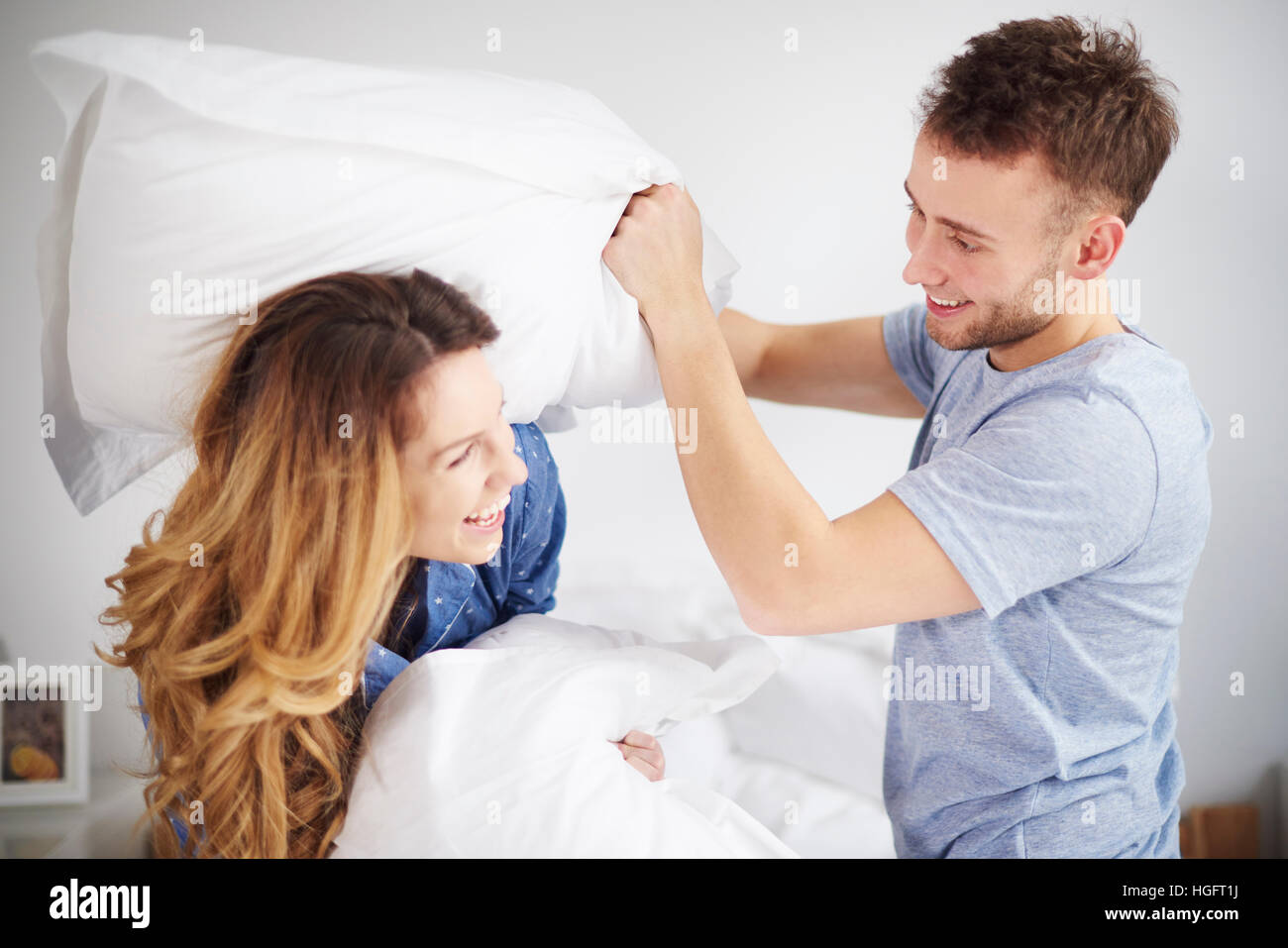 Couple having pillow fight in bedroom Stock Photo
