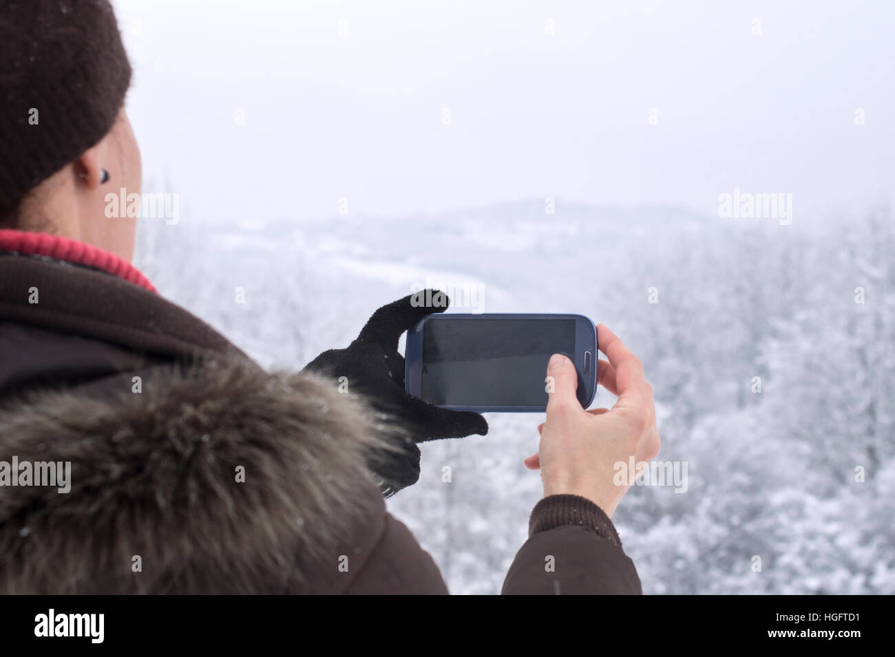woman taking photo with smartphone in winter. Stock Photo
